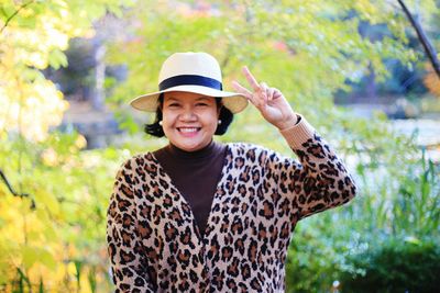 Portrait of woman gesturing while standing at park