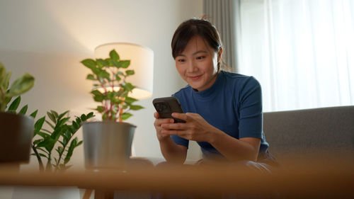 Young woman using mobile phone at home