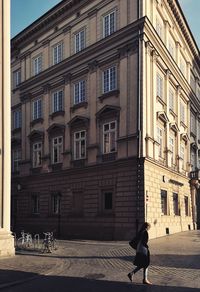 Woman walking on street against building in city