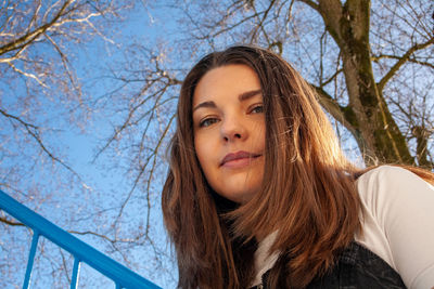 Portrait of young woman against bare tree