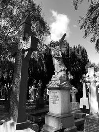 Statue in cemetery against sky