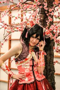 Portrait of smiling young woman against red flowering plants