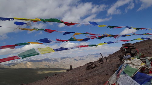 Low angle view of flags hanging on mountain against sky