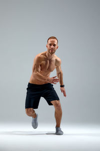 Portrait of shirtless man exercising against white background