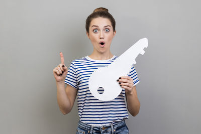 Portrait of smiling woman holding paper while standing against wall