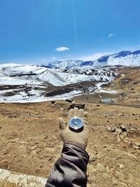 Low section of person on snowcapped mountain against sky