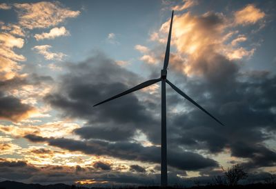 Low angle view of silhouette crane against dramatic sky