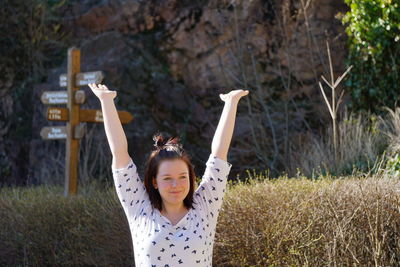 Smiling teenage girl with arms raised standing on field