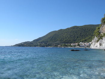 Boats in calm sea against clear sky