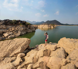 Man standing on rock by mountain against sky