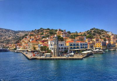 View of townscape by sea against clear blue sky