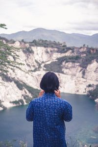 Rear view of woman looking at mountains against sky