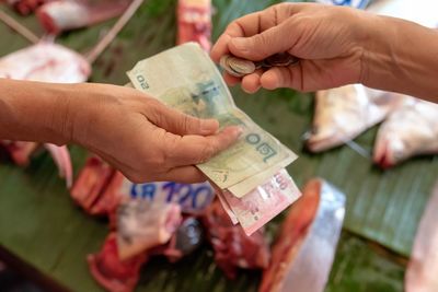 Cropped hands of person giving currency to seller at store