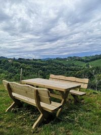 Empty chairs on field against sky