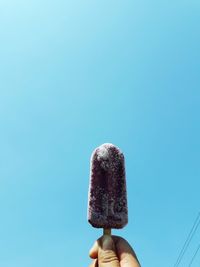 Human hand holding ice cream against clear sky