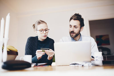 Surface level view of couple shopping online from laptop and credit card at home