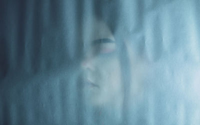 Woman seen through curtain at home