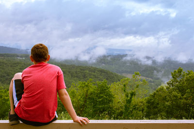 Rear view of man looking at mountains against sky