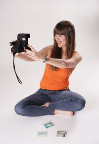 Beautiful woman taking selfie through camera against white background