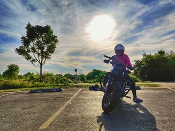 Man riding motorcycle on road against sky