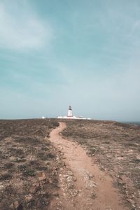 Lighthouse amidst sea and buildings against sky