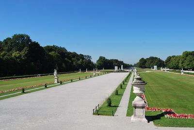 Pathway in park against clear blue sky