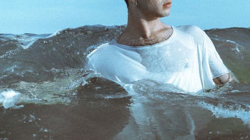 Young man swimming in splashing sea