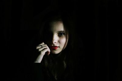 Portrait of young woman against black background
