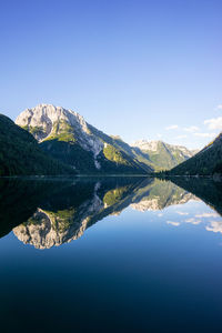 Reflection of mountains in lake against clear blue sky