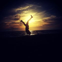 Silhouette woman on beach against sky during sunset