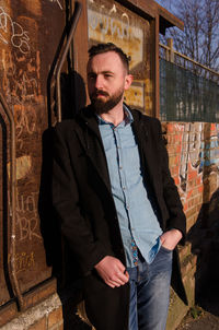 Portrait of young man standing against built structure