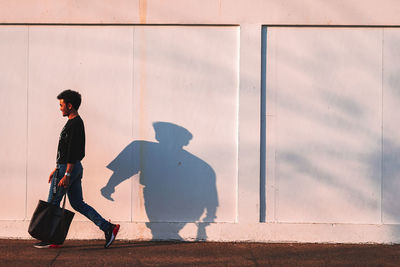 Side view of man walking against wall