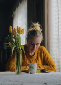 Young woman with flowers on table