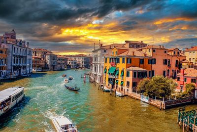 Canal amidst buildings against sky during sunset