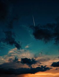 Low angle view of vapor trails in sky at sunset