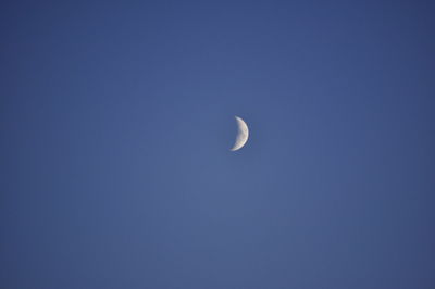 Low angle view of moon against blue sky