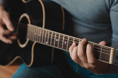 Midsection of man playing guitar