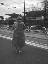 Rear view of woman walking on road against sky