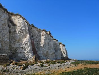 Low angle view of rocky mountain against clear blue sky