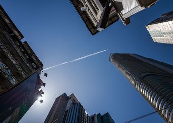 Directly below view of vapor trail over buildings in city