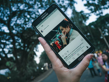 Midsection of man using mobile phone against tree