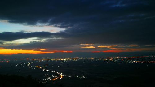 Aerial view of illuminated cityscape against dramatic sky