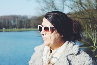 Close-up of woman looking away while standing against lake