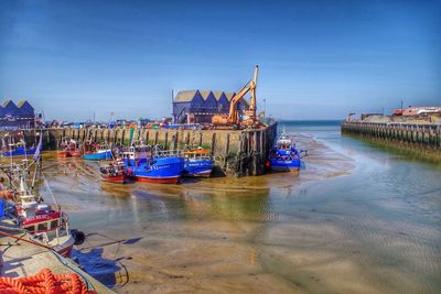 Boats moored in sea against buildings in city