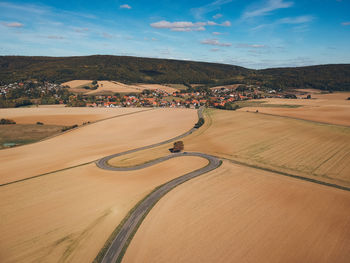 High angle view of road amidst field against sky