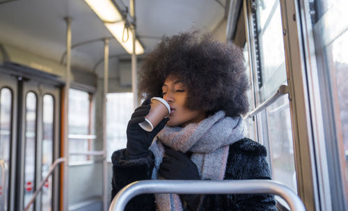 Young woman holding coffee cup sitting in bus