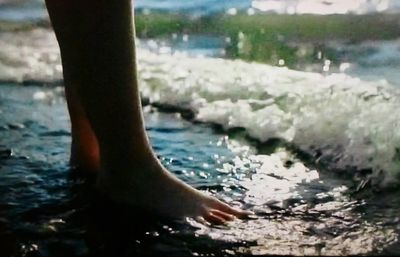 Low section of woman standing in sea