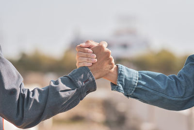 Midsection of man holding hands against blurred background