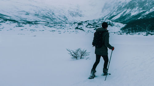 Rear view of man standing on snowcapped mountain