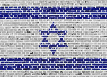 Close-up on a brick wall with the flag of israel painted on it.